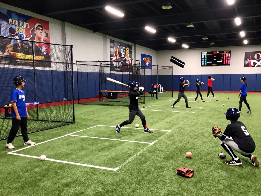 Young athletes at hitclub practicing baseball in vibrant gym.