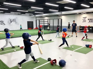 Youth athletes practicing at Hitclub baseball training facility, showcasing dynamic sports environment with coaches and equipment.